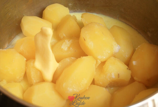 Giet de aardappels af en stamp ze fijn