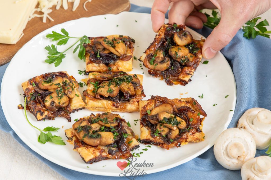 Bladerdeeghapjes met gekarameliseerde rode ui, champignons en Gruyère uit de oven