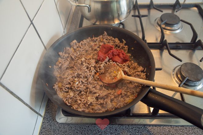 Voeg de tomatenpuree toe en bak 1 minuut mee.