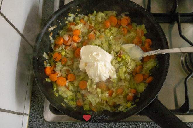 Roer de crème fraîche erdoor en schep in de ovenschaal