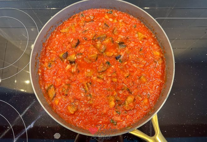 Doe de gebakken aubergine bij de tomatensaus